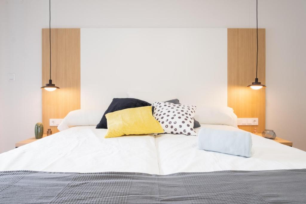 a bed with a white comforter and pillows at Pensión Arroka in San Sebastián