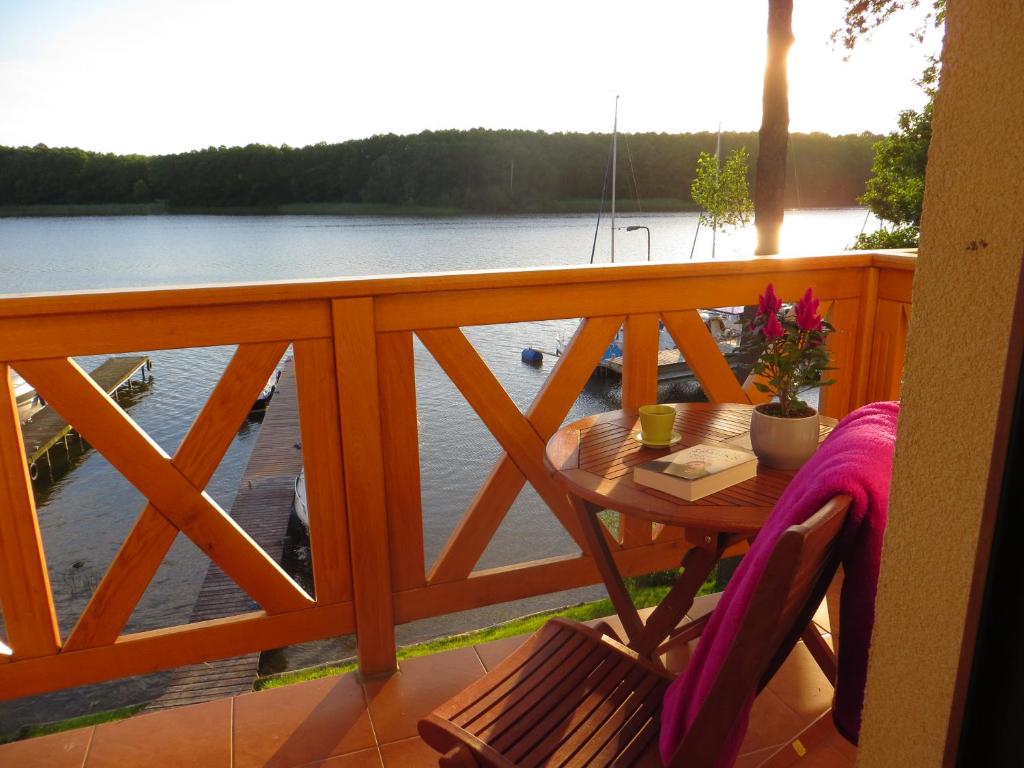 een tafel op een balkon met uitzicht op het water bij Domek letniskowy Bliżej natury in Iława