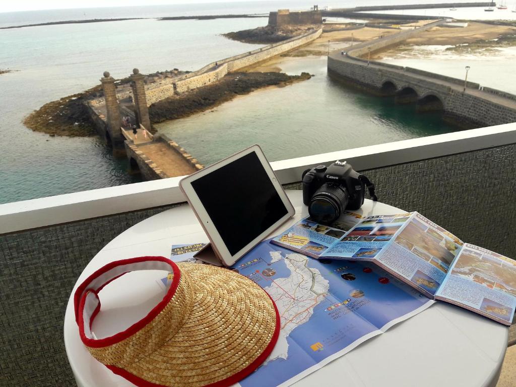 una mesa con sombrero, ordenador portátil y mapa en Hotel Miramar, en Arrecife