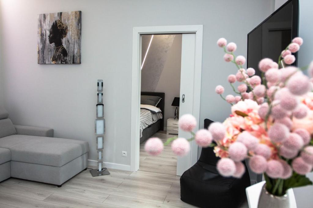 ein Wohnzimmer mit einem Sofa und einer Vase mit rosa Bällen in der Unterkunft Novel in Warschau