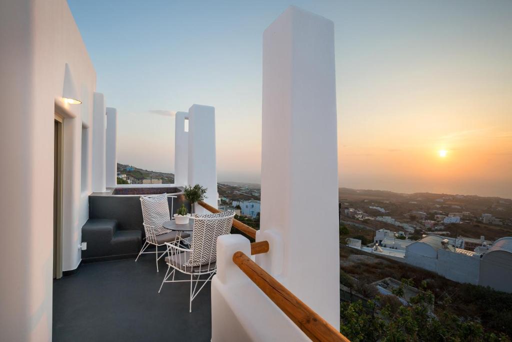 a balcony with a table and chairs at sunset at Nectarios Villa - Studios & Suites Adults Only in Fira
