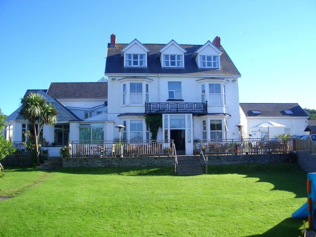 a large white house with a lawn in front of it at Malin House Hotel in Saundersfoot