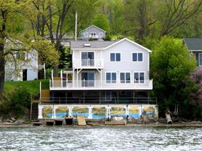 una gran casa blanca en la orilla de un cuerpo de agua en Chateau du Lac, en Richfield Springs