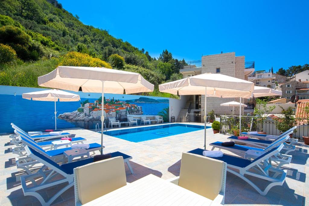 a swimming pool with chairs and umbrellas and a pool at Apartments Jovan in Sveti Stefan