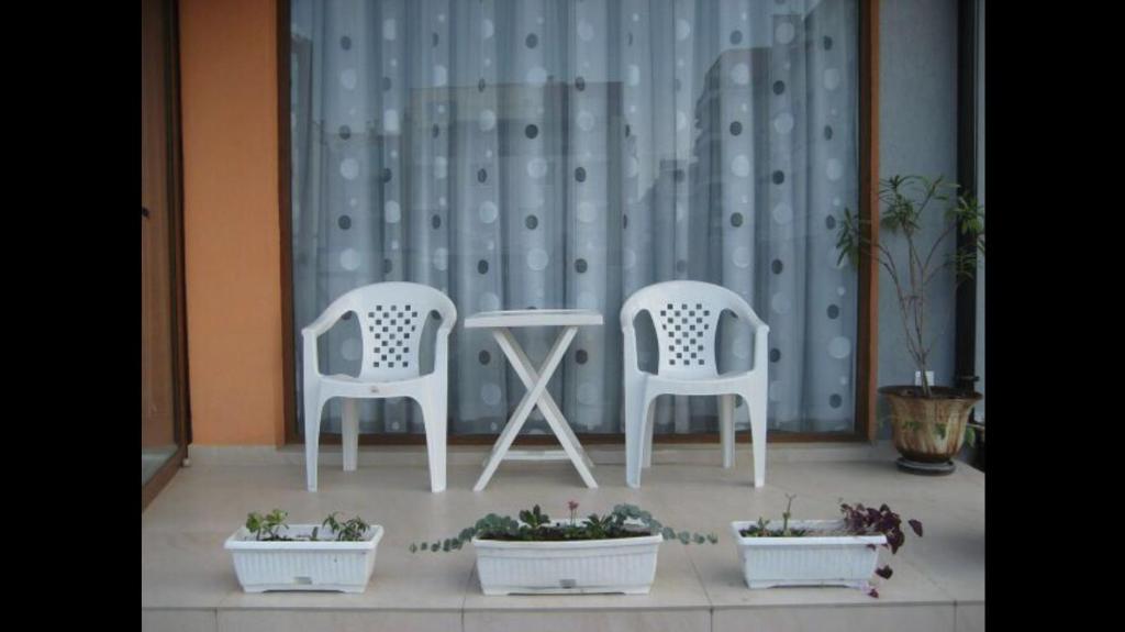 twee witte stoelen en een tafel en wat potplanten bij GoodRest Nesebar in Nesebar