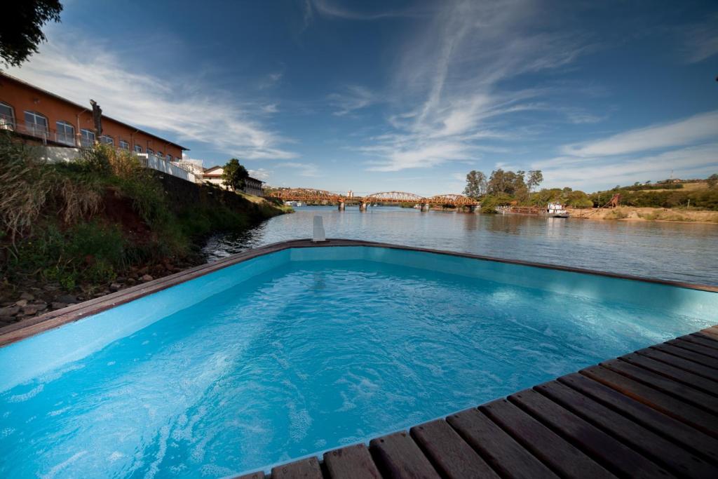 a large blue swimming pool next to a river at Tapri - Hotel Flutuante in Barra Bonita