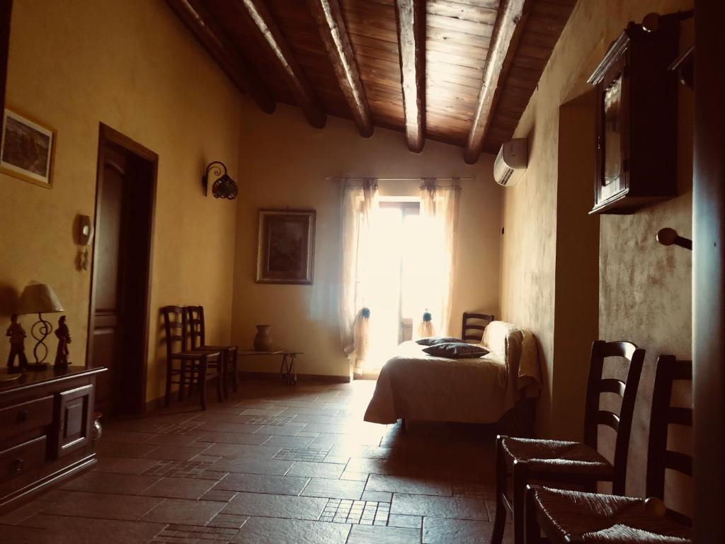 1 dormitorio con 1 cama, ventana y sillas en Agriturismo Ilardo en Collesano