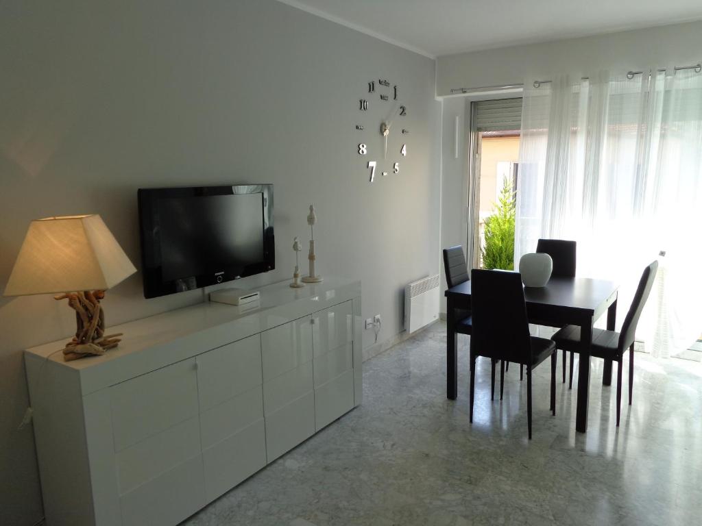 a dining room with a table and a tv on a white wall at Residence Albert Premier in Menton
