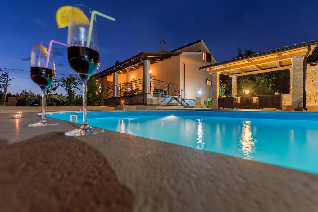 a pool with two glasses of wine in front of a house at Holiday Home Villa Lucia in Vodnjan