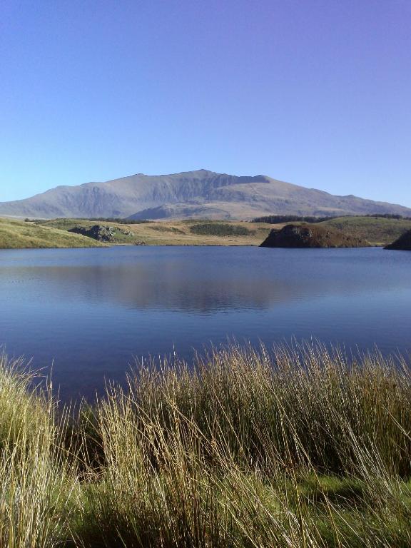 a large body of water with mountains in the background at Samuel cottage in Caernarfon