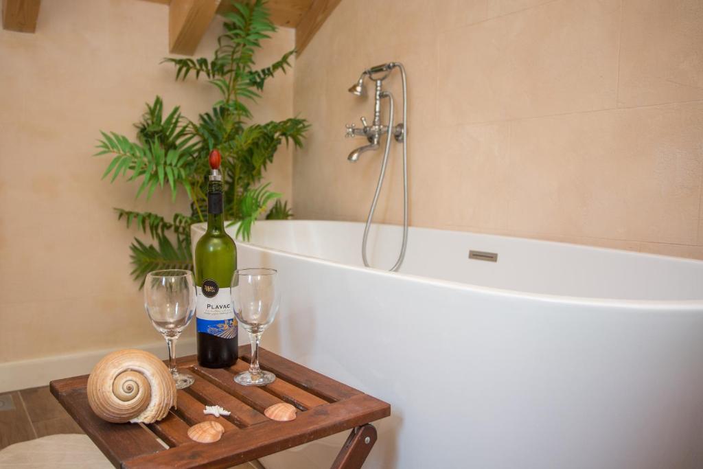 a bathroom with a bath tub and a table with wine bottles and glasses at Captain's Attic in Račišće