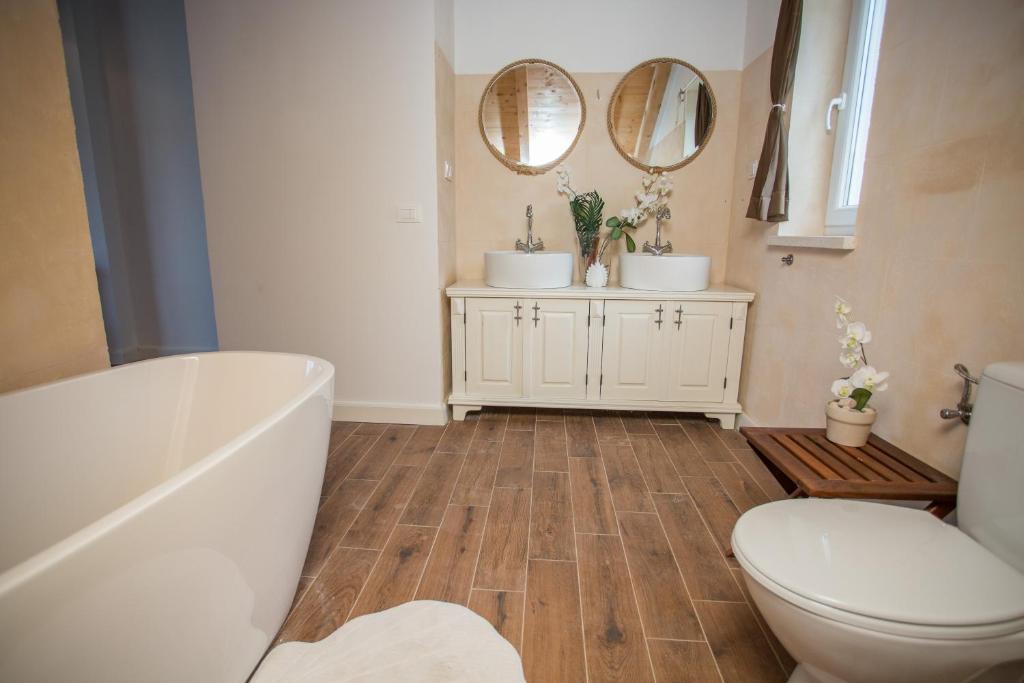 a bathroom with a tub and a toilet and two mirrors at Captain's Attic in Račišće