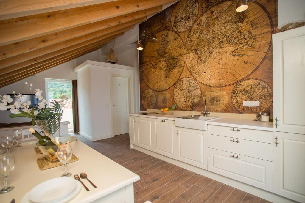 a kitchen with white cabinets and a map on the wall at Captain's Attic in Račišće