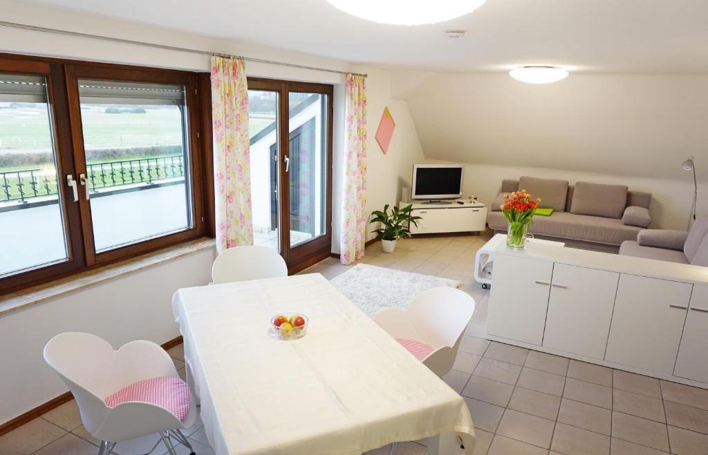 een woonkamer met een witte tafel en stoelen bij Rennbahn - Life Iffezheim; Wohnen mit Rennbahnblick in Iffezheim