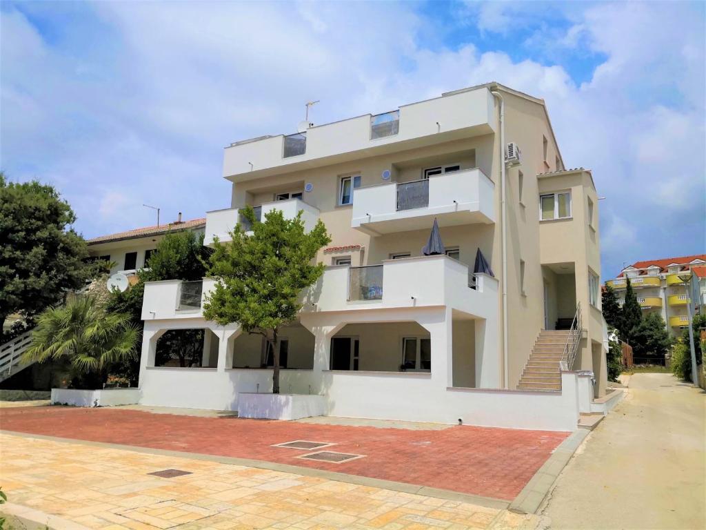 a white building with a tree in front of it at Villa Gaj in Novalja