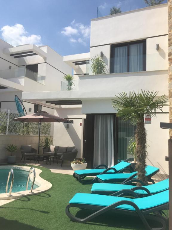 a row of blue lounge chairs next to a building at Villa Bianco in Orihuela Costa