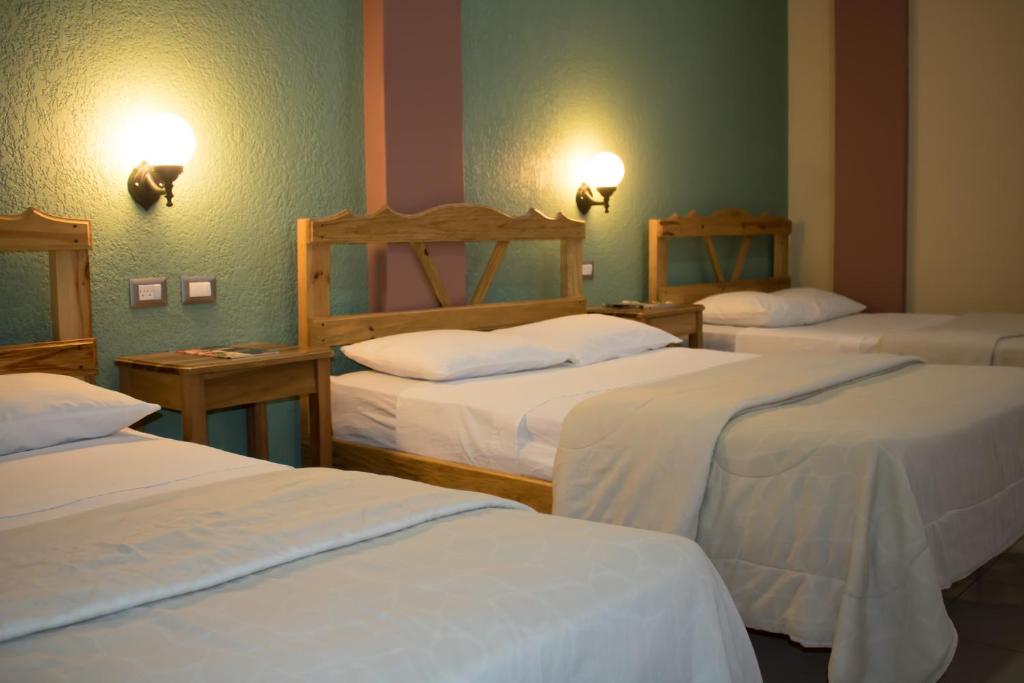 a room with three beds with white sheets at Hotel San Jorge in Santa Rosa de Copán