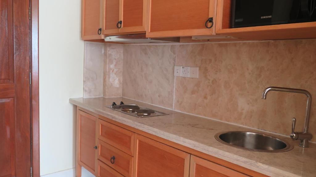 eine Küche mit Spüle und Holzschränken in der Unterkunft Langkawi Lagoon Resort Seaview in Pantai Cenang