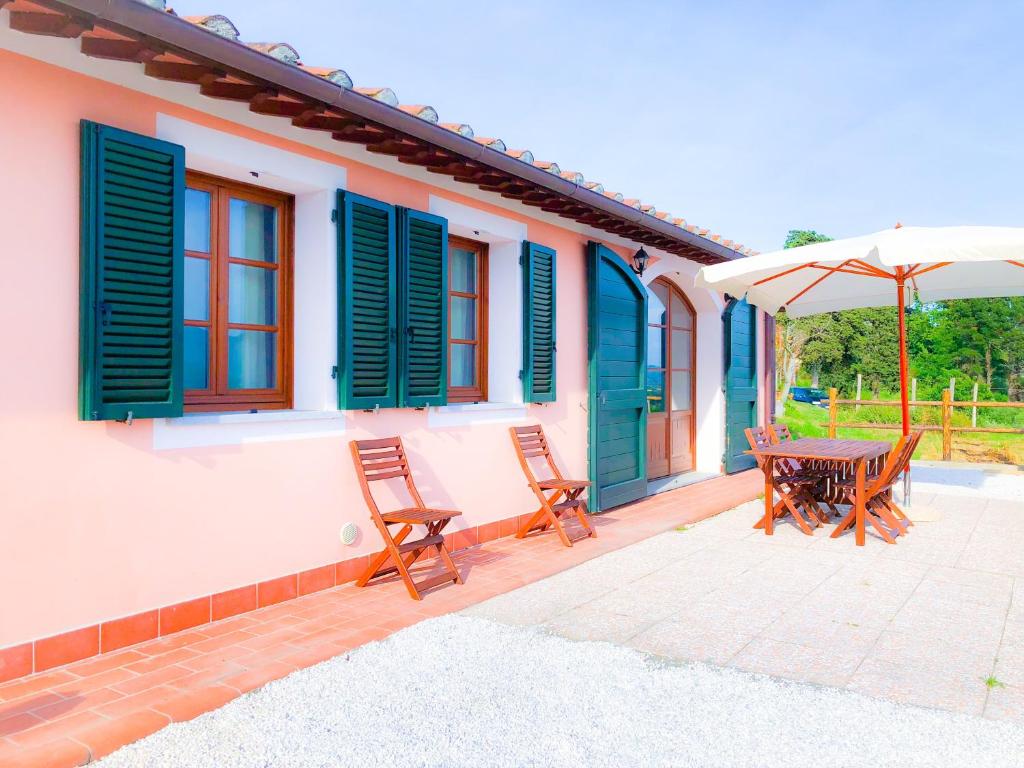 eine Terrasse mit einem Tisch, Stühlen und einem Sonnenschirm in der Unterkunft Villino Al Dotto Country House in Lucca