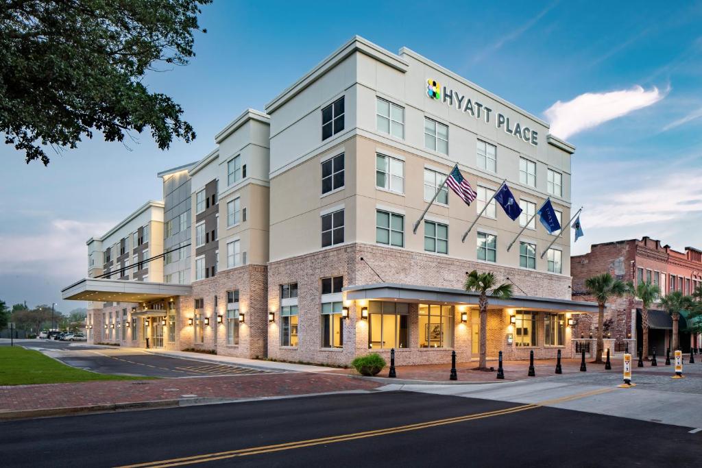 a large white building with two american flags on it at Hyatt Place Sumter/Downtown in Sumter