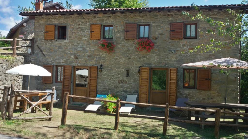 una casa de piedra con mesas y sombrillas delante en Casello Orecchiella, en San Romano