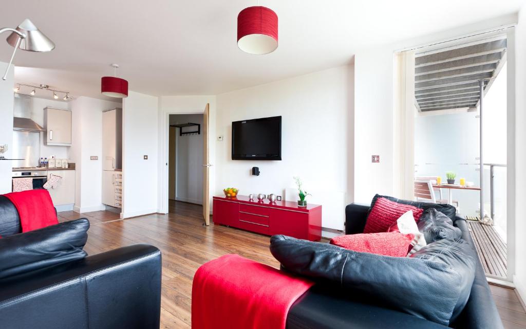 a living room with black leather furniture and a red couch at Apartment in Central MK - Bed Choice of 1 Super-king Or 2 Singles and also 2 Sofa Beds - Free Parking and Smart TV - Contractors, Relocation, Business Travellers in Milton Keynes