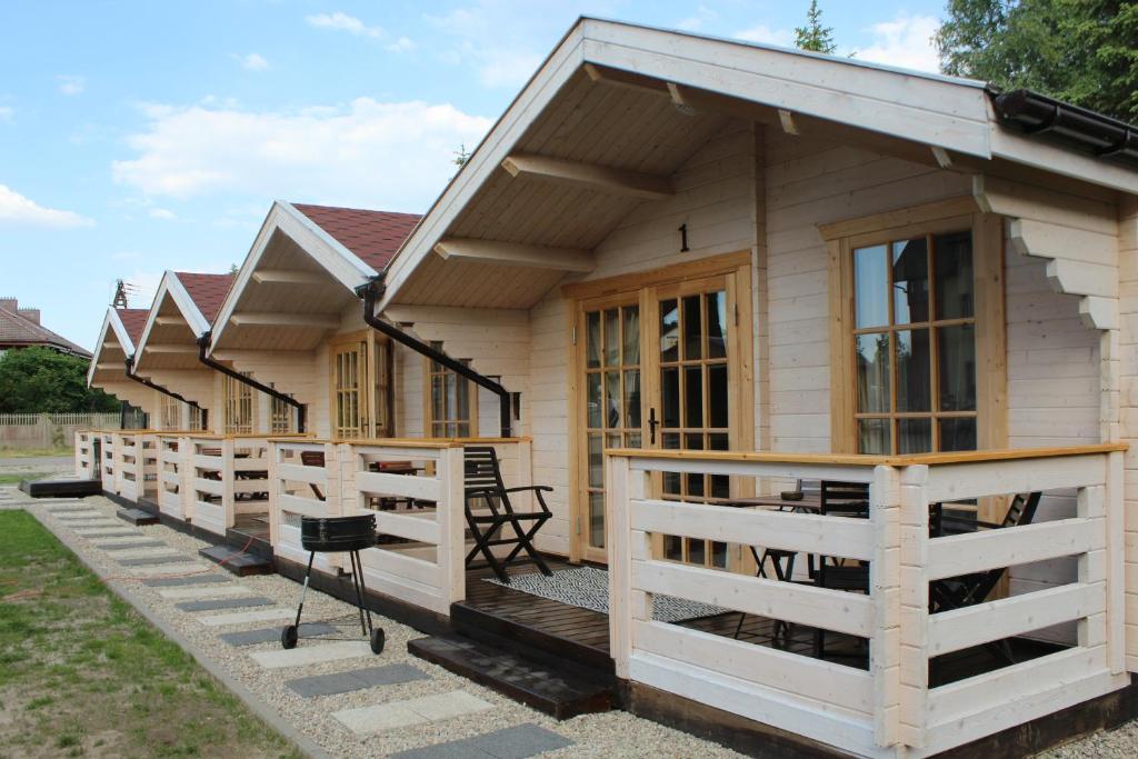una casa pequeña con porche y valla en Domki Letniskowe i Pokoje NATALIE, en Mielno