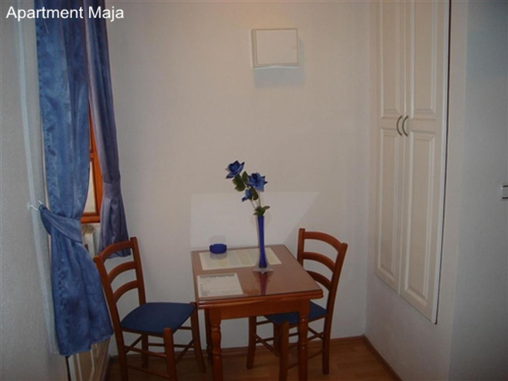 einen Tisch mit Stühlen und eine Vase mit Blumen darauf in der Unterkunft Maja Apartments in Trogir