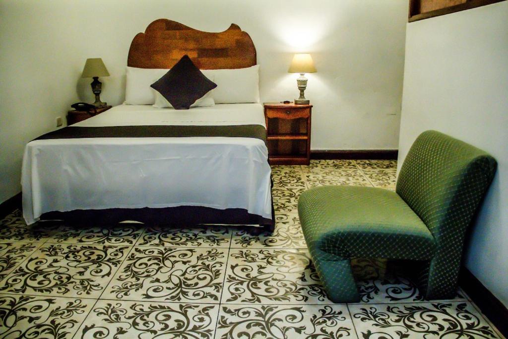 a hotel room with a bed and a chair at Epoca Iquitos in Iquitos