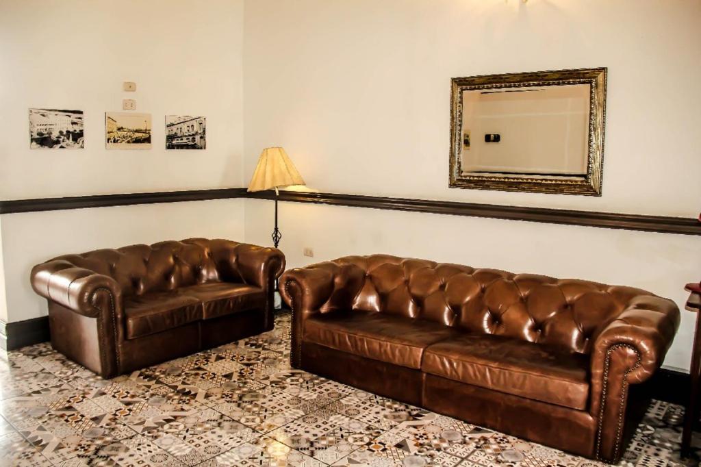 a living room with two leather couches and a mirror at Epoca Iquitos in Iquitos