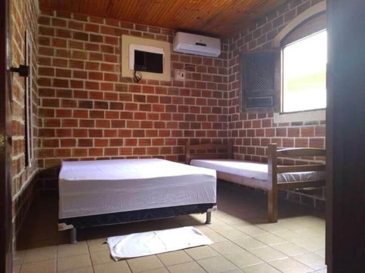 a room with two beds and a brick wall at Casa Centro de Maragogi in Maragogi