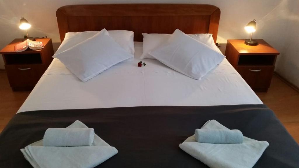 a large white bed with two pillows on it at Apartments Klanac in Tkon