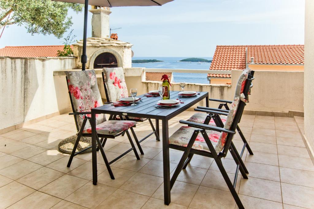 a table and chairs on a patio with an umbrella at Apartments Tatjana Dominis in Hvar