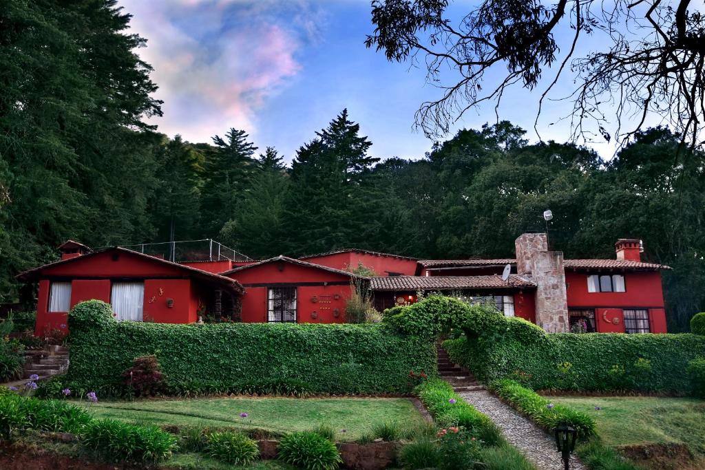 une maison rouge avec un jardin en face dans l'établissement Rancho Yapalpan, à El Oro de Hidalgo