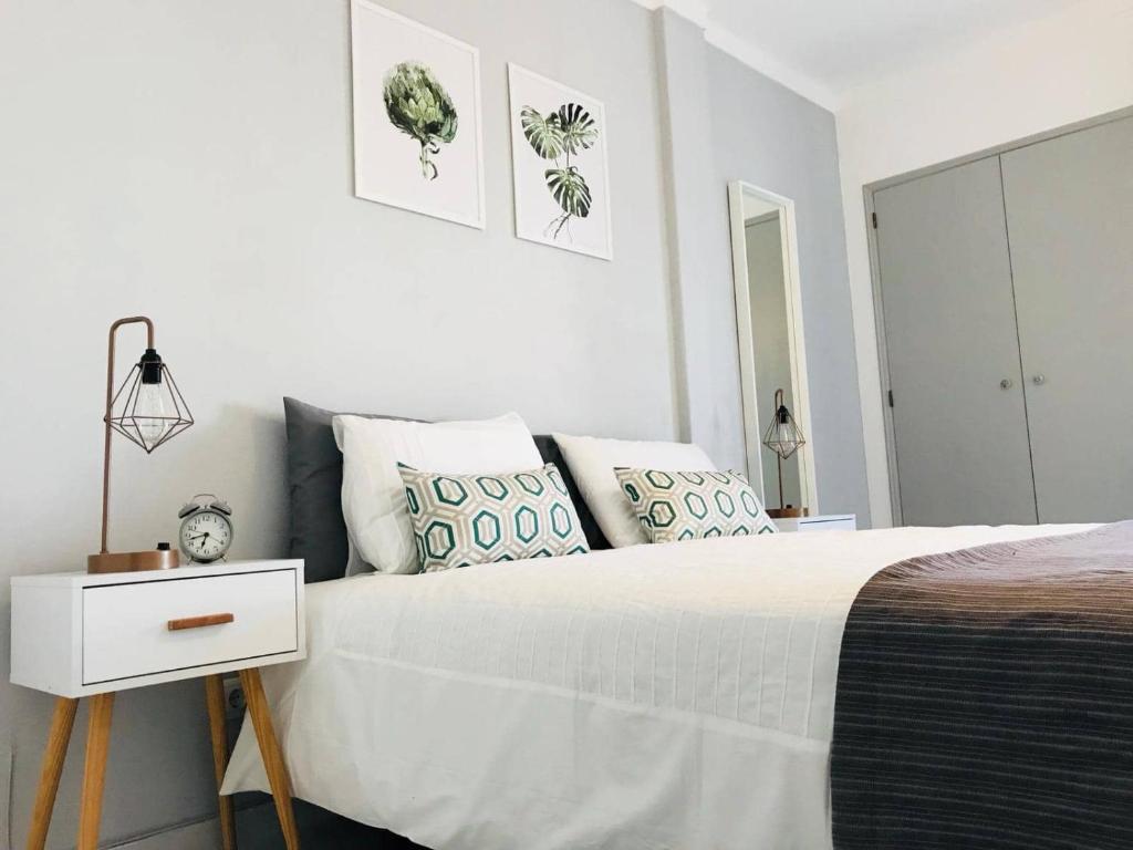a white bedroom with a bed and a night stand at Ferragudo'Spot in Ferragudo