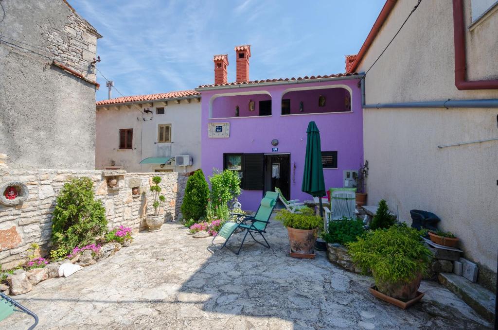 ein lila Gebäude mit Stühlen und einem Sonnenschirm in einem Innenhof in der Unterkunft House Rita in Rakalj