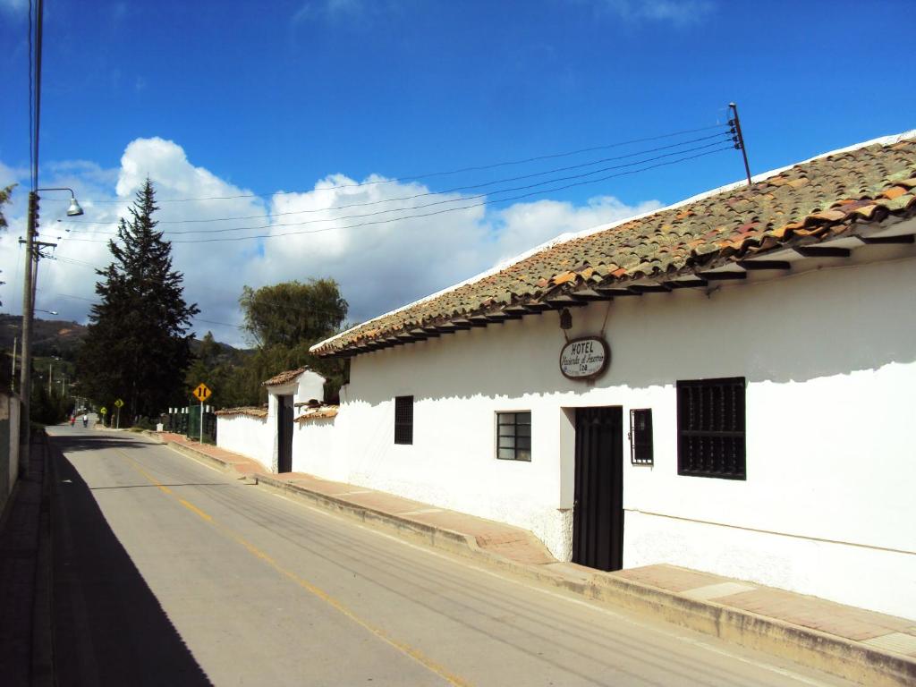 een wit gebouw aan de kant van een weg bij Hotel Hacienda El Aserrio in Iza