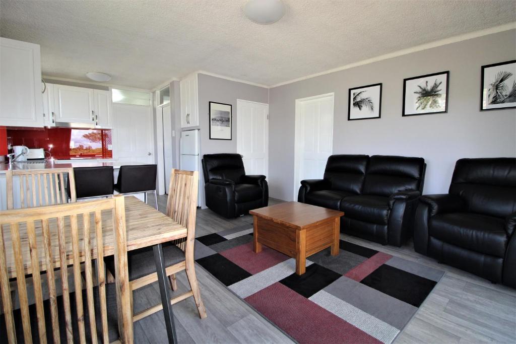 a living room with black leather furniture and a table at Beachfront 3, 25 Willow Street in Crescent Head