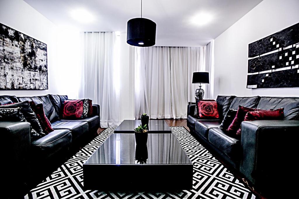 a living room with black leather couches and a glass table at Lindo Apto Frente ao Mar in Rio de Janeiro