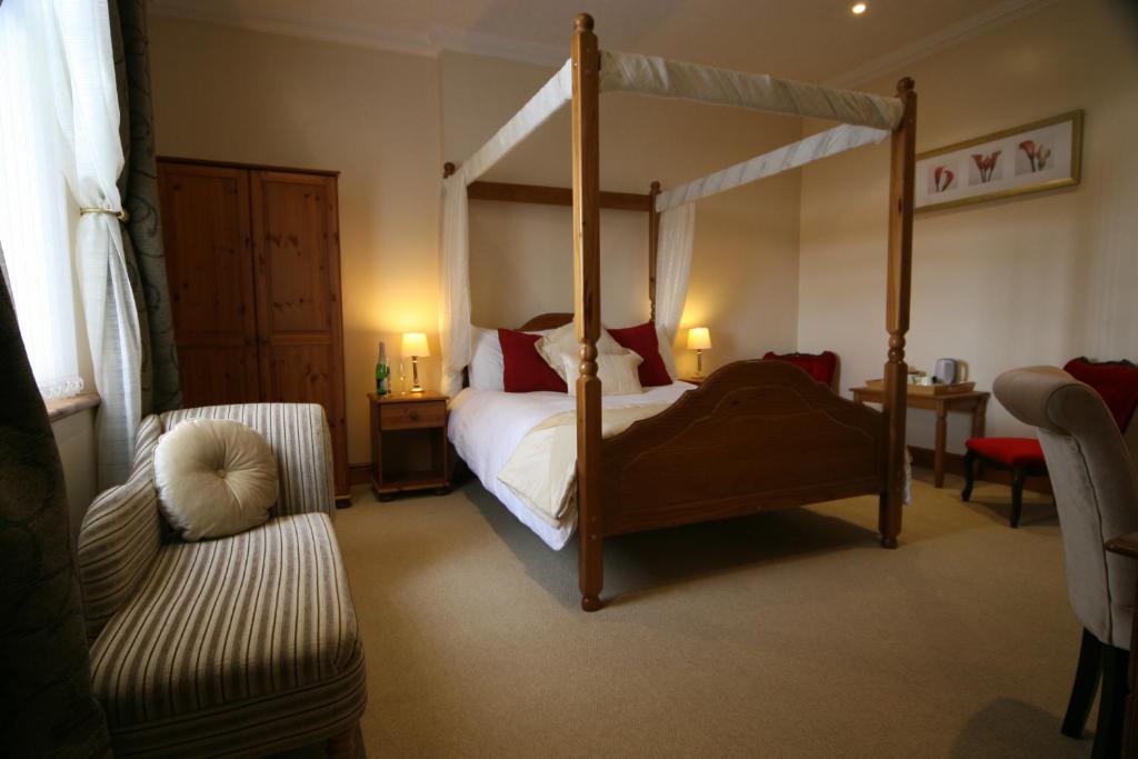 a bedroom with a canopy bed and a chair at Anvil View Guest House in Gretna Green