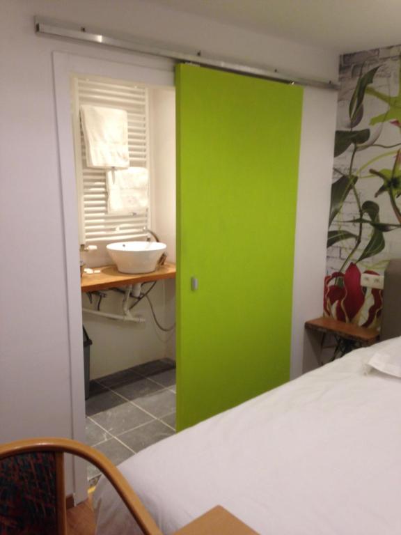 eine grüne Tür, die zu einem Schlafzimmer mit einem Waschbecken führt in der Unterkunft Hotel De Backer in Knokke-Heist