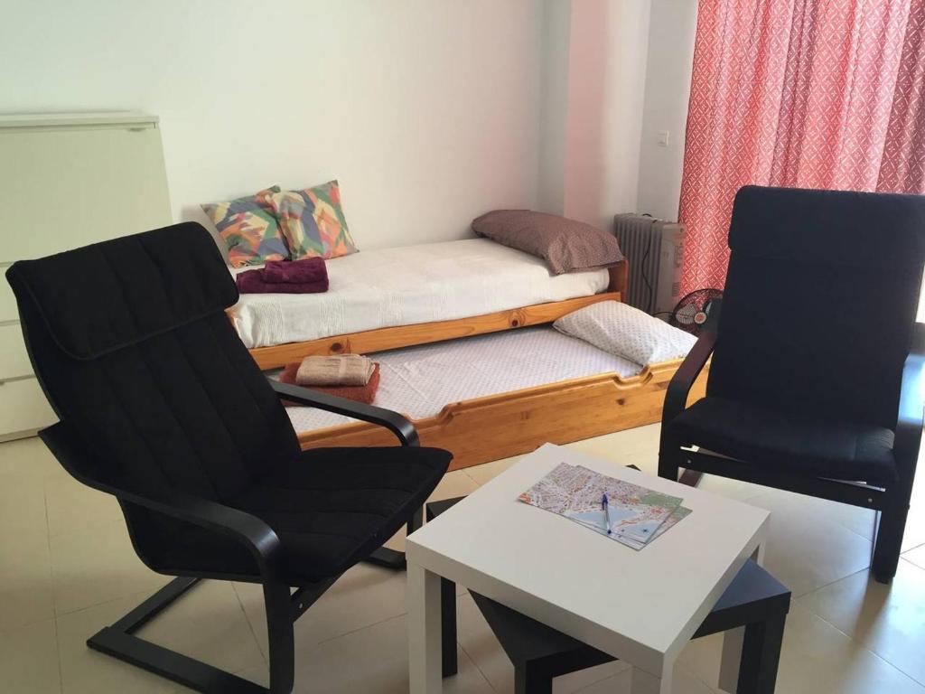 マラガにあるCity Sunny Apartmentの椅子2脚、ベッド1台、テーブルが備わる客室です。