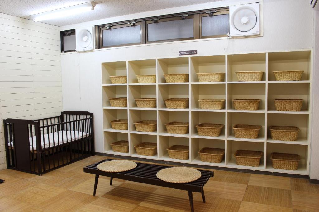 a room with a shelf with baskets and a bench at Miyajima Seaside Hotel in Miyajima