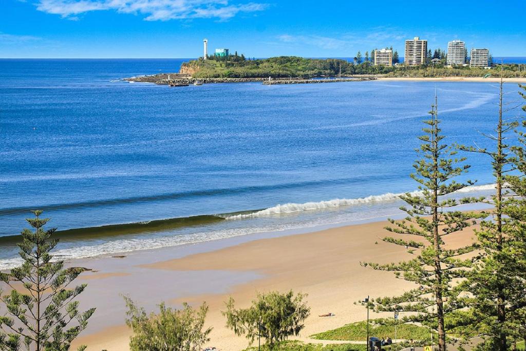 una playa frente al océano con edificios de fondo en Malibu Apartments, en Mooloolaba