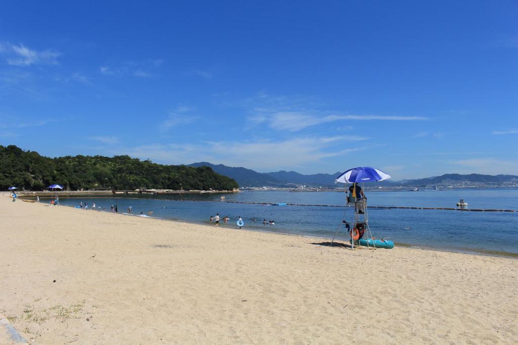 a person standing under an umbrella on a beach at Miyajima Seaside Hotel in Miyajima