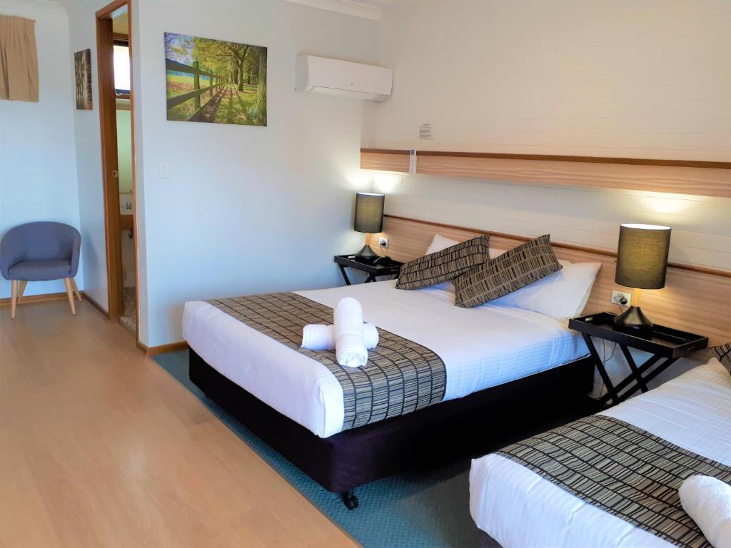 a hotel room with two beds and a chair at Kurri Motor Inn in Kurri Kurri