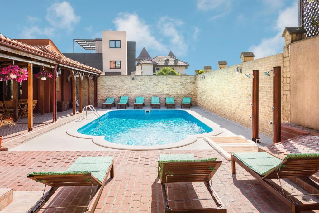 a swimming pool with chairs and a building at Vila Patricia in Eforie Sud