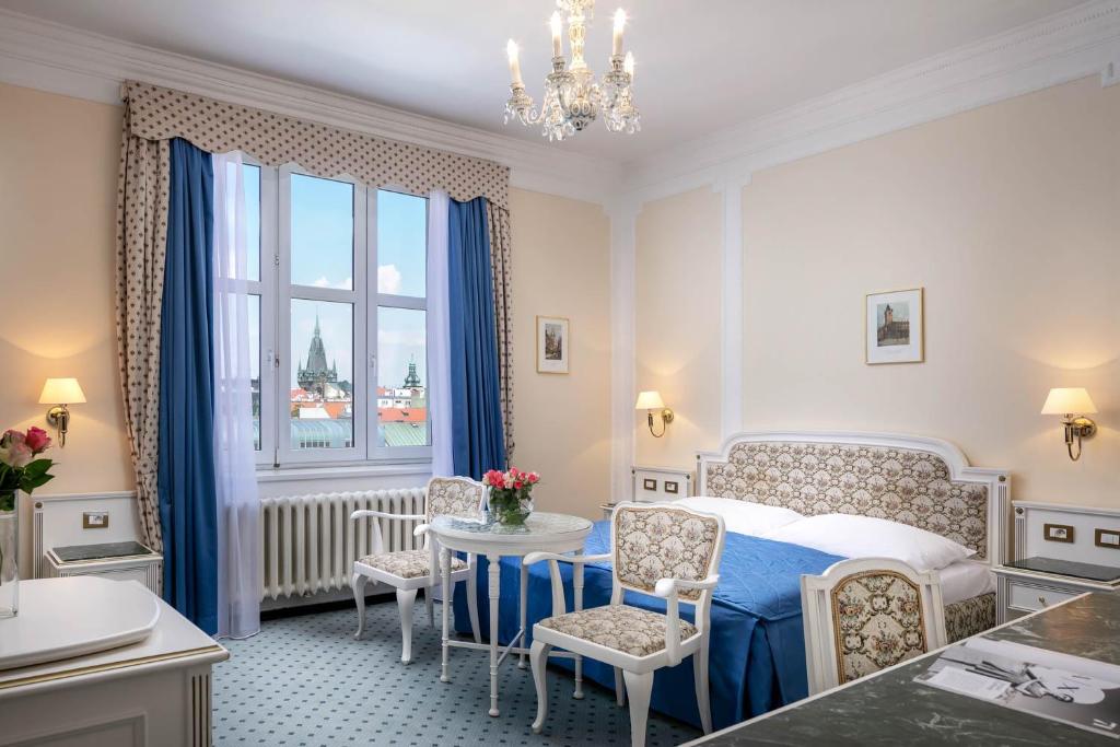 1 dormitorio con 1 cama, mesa y sillas en Ambassador Zlata Husa, en Praga