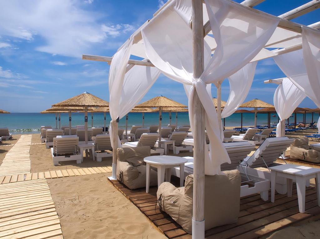 een restaurant op het strand met stoelen en parasols bij Amaryllis Beach Hotel in Chrissi Akti