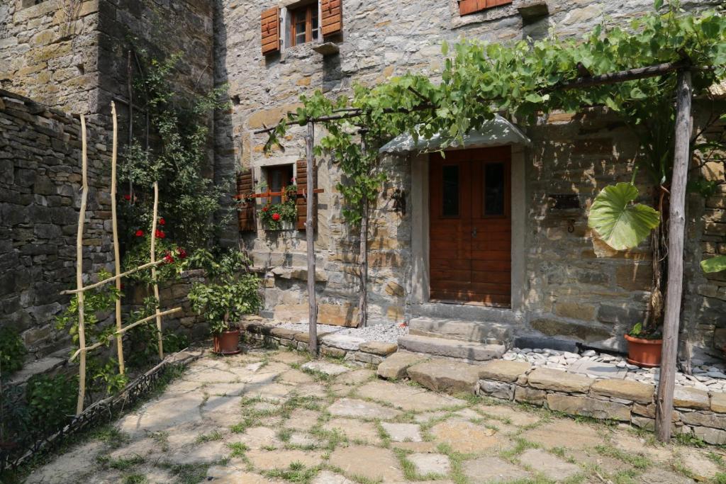 une ancienne maison en pierre avec une porte et quelques plantes dans l'établissement Istrian Experience, à Sočerga